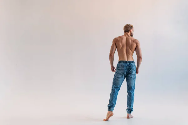 A young Man of strong constitution with a relief figure of a bodybuilder with a beautiful torso. Shooting in the studio on a white background.