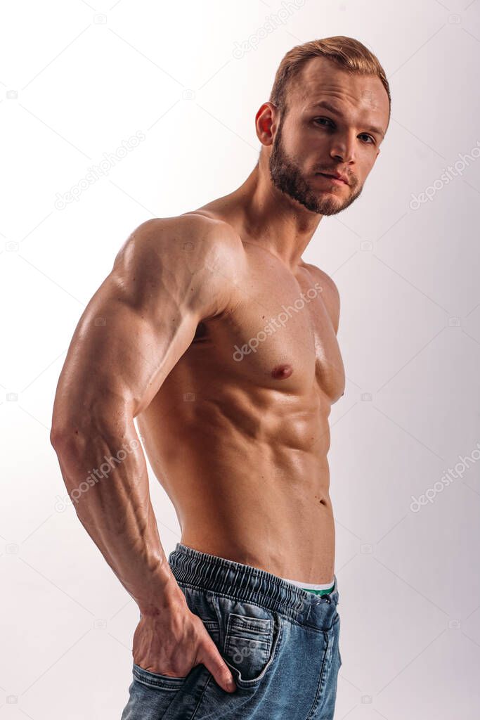 A young Man of strong constitution with a relief figure of a bodybuilder with a beautiful torso. Shooting in the studio on a white background.