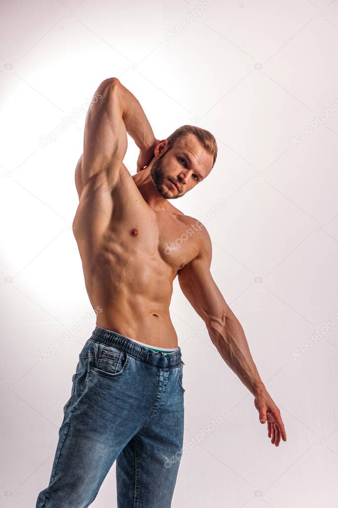 A young Man of strong constitution with a relief figure of a bodybuilder with a beautiful torso. Shooting in the studio on a white background.