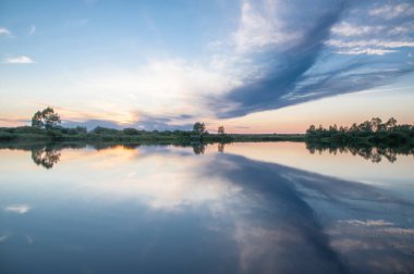 Rusya 'nın Bashkortostan cumhuriyetinin Agidel kasabasındaki küçük nehrin yakınındaki bir ormanda günbatımının tadını çıkarıyorum.