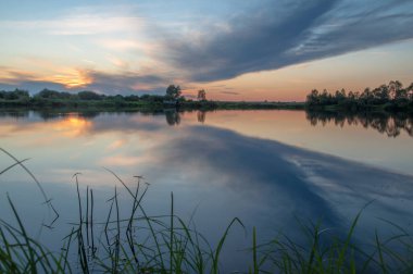 Rusya 'nın Bashkortostan cumhuriyetinin Agidel kasabasındaki küçük nehrin yakınındaki bir ormanda günbatımının tadını çıkarıyorum.