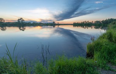 Rusya 'nın Bashkortostan cumhuriyetinin Agidel kasabasındaki küçük nehrin yakınındaki bir ormanda günbatımının tadını çıkarıyorum.