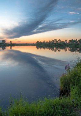 Rusya 'nın Bashkortostan cumhuriyetinin Agidel kasabasındaki küçük nehrin yakınındaki bir ormanda günbatımının tadını çıkarıyorum.