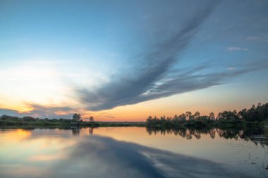 Rusya 'nın Bashkortostan cumhuriyetinin Agidel kasabasındaki küçük nehrin yakınındaki bir ormanda günbatımının tadını çıkarıyorum.