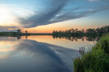 Rusya 'nın Bashkortostan cumhuriyetinin Agidel kasabasındaki küçük nehrin yakınındaki bir ormanda günbatımının tadını çıkarıyorum.