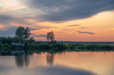 Rusya 'nın Bashkortostan cumhuriyetinin Agidel kasabasındaki küçük nehrin yakınındaki bir ormanda günbatımının tadını çıkarıyorum.