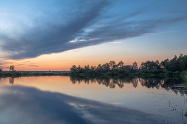Rusya 'nın Bashkortostan cumhuriyetinin Agidel kasabasındaki küçük nehrin yakınındaki bir ormanda günbatımının tadını çıkarıyorum.