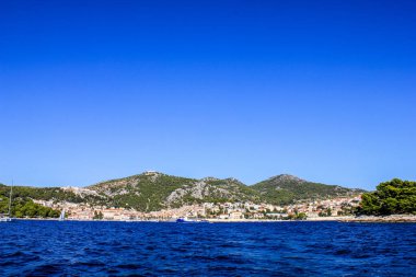 Hvar, Hırvatistan - 2 Ekim 2011: Güneşli bir günde Hvar yakınlarındaki Geleneksel Eski Ev ve Teknelerin Görünümü