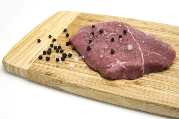 Raw beef steak from young bull with salt and pepper on cutting board — Stock Photo, Image