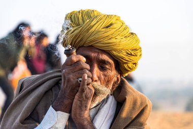 Kasım 2019 Pulkar Rajasthan: Pulkar deve festivalinde chiilam tüttüren yaşlı bir kabilenin portresi