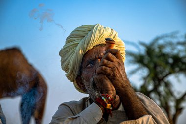 Kasım 2019 Pulkar Rajasthan: Pulkar deve festivalinde chiilam tüttüren yaşlı bir kabilenin portresi