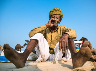 İtici deve festivalinde sigara içen adamın portresi.