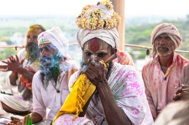 Holi festivalinde Barsana 'da biber tüttüren bir keşiş seçici bir şekilde konuya odaklanıyor ve gürültü ve tahıl ekliyor..