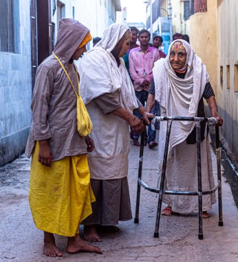 Hindistan sokaklarındaki Holi Festivali sırasında yaşlı bayanın portresi seçici bir şekilde konuya odaklanmış ve gürültü ve tahıl eklenmiş..