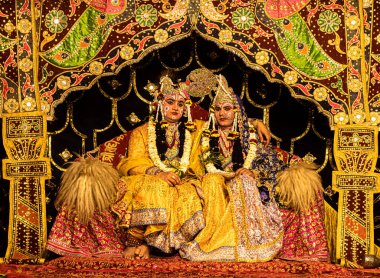 Sahnede Krishna ve Radha 'yı temsil eden genç aktör seçici bir odak noktasıyla sahnede..