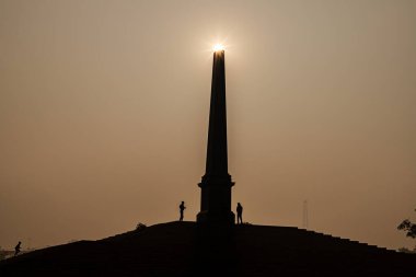Delhi 'de gün doğumuyla birlikte taç giyme parkında güzel bir siluet manzarası..
