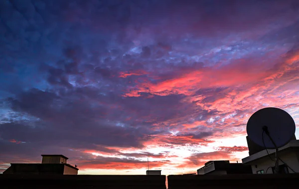 colorful silhouette of the buildings over colorful sky background with manson clouds.