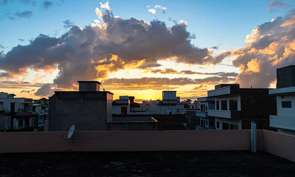 colorful silhouette of the buildings over colorful sky background with manson clouds and sunset or sun star.