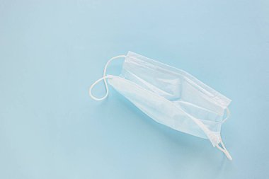  Mavi arka planda lastik kulaklıklı tıbbi maske kullanılmış. Virüs ve bakterilerden koru. Sancak konsepti