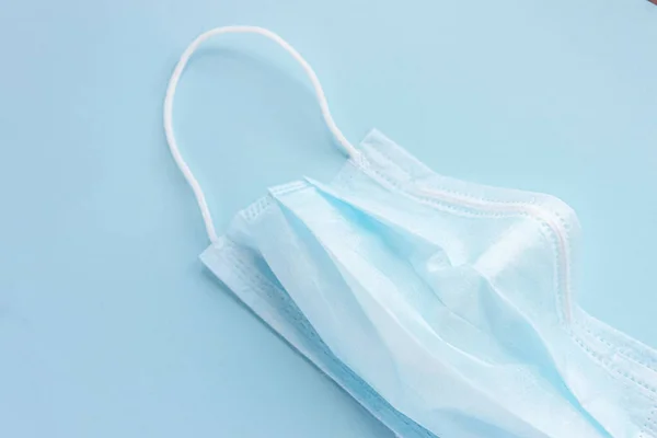  Mavi arka planda lastik kulaklıklı tıbbi maske kullanılmış. Virüs ve bakterilerden koru. Sancak konsepti