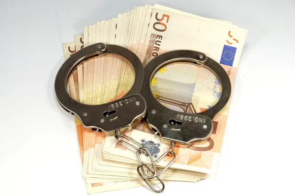 Geld und Handschellen — Stockfoto