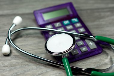 Ahşap zemin üzerinde steteskop ve hesap makinesinin yakın çekim görüntüsü