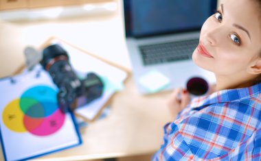 Masada dizüstü bilgisayarla oturan kadın fotoğrafçı.