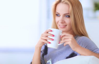 evde kanepenin üzerine bir fincan genç güzel kadın