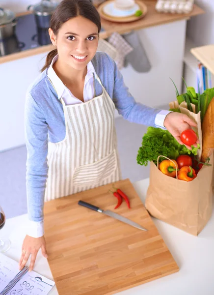 Mujer haciendo comida saludable de pie sonriendo en la cocina —  Fotos de Stock