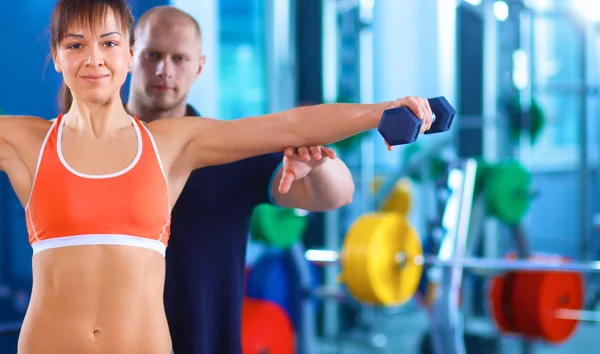 Hermosa mujer en el gimnasio haciendo ejercicio con su entrenador — Foto de Stock