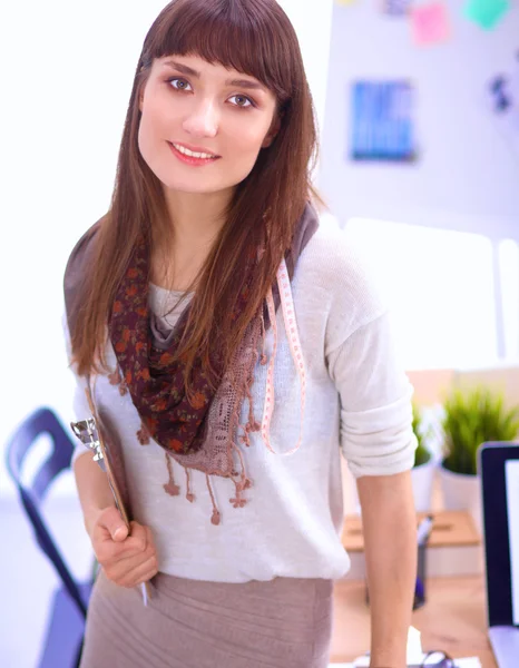 Young attractive fashion designer standing by desk in office, holding folders — Stock Photo, Image