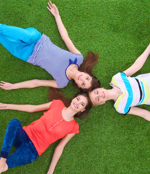 Jonge smilling vrouwen liggend op groen gras — Stockfoto