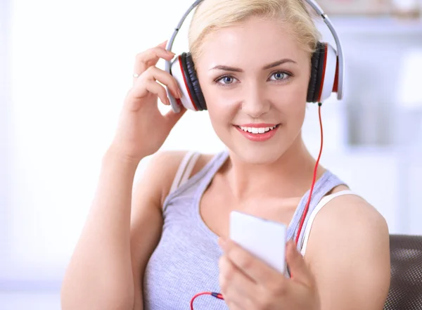 Jeune belle femme à la maison assise sur un canapé et écoutant de la musique — Photo