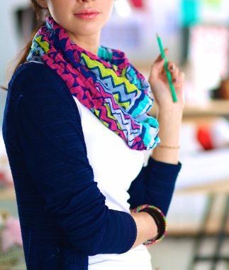 Güzel moda tasarımcısı stüdyoda duruyor.