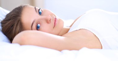 Genç ve güzel bir kadın yatakta yatıyor.