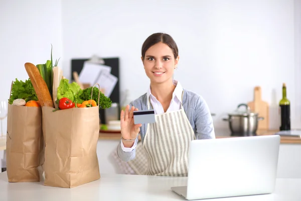 Smiling woman online shopping using computer and credit card in kitchen — Stock Photo, Image