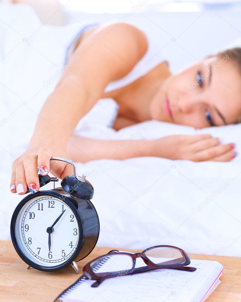 A young woman putting her alarm clock off in the morning