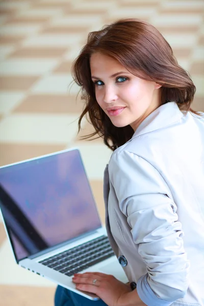 Unga leende kvinna sitter med bärbar dator — Stockfoto