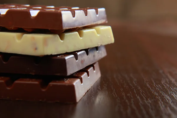 Stack of chocolate pieces on a wood background — Stock Photo, Image