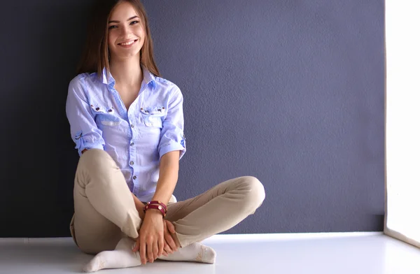 Jovem mulher sentada no chão perto da parede escura — Fotografia de Stock