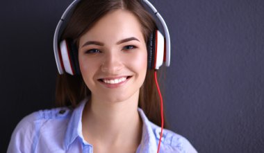 Duvara yakın katta oturan kulaklıklar ile gülümseyen kız