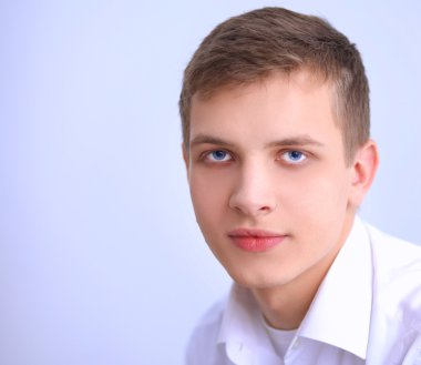 Gri arka plan üzerinde oturan gülümseyen genç adam portresi