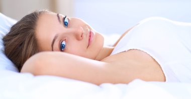 Genç ve güzel bir kadın yatakta yatıyor.