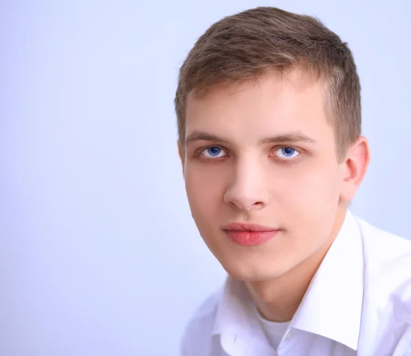 Портрет молодого чоловіка, який посміхається сидячи на сірому фоні — стокове фото