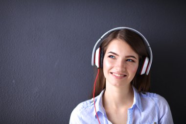 Duvara yakın katta oturan kulaklıklar ile gülümseyen kız