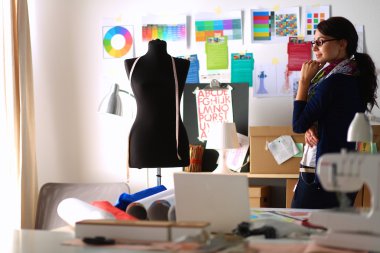 Güzel moda tasarımcısı stüdyoda duruyor.