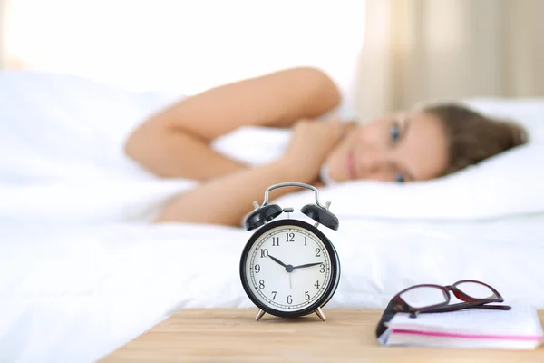 Una mujer joven apagando su despertador por la mañana — Foto de Stock