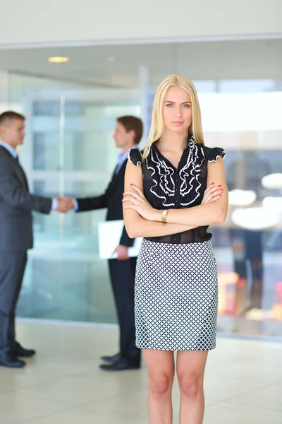 Portret van jonge zakenvrouw in functie met collega 's op de achtergrond — Stockfoto