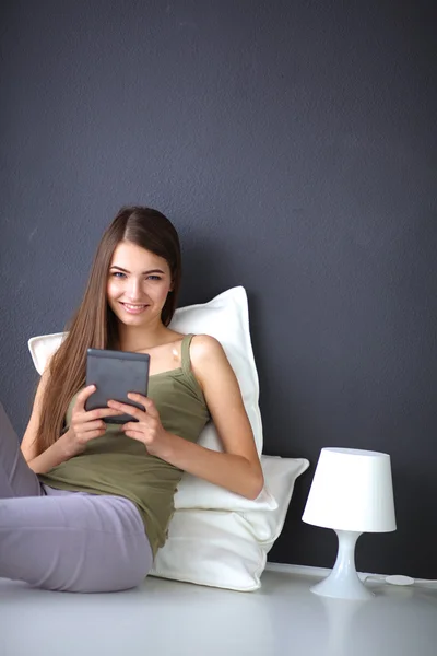 Mujer morena bonita sentada en el suelo con una almohada y mesa de avión — Foto de Stock