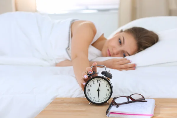 Una mujer joven apagando su despertador por la mañana — Foto de Stock